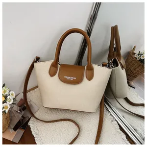 Close-up of retro canvas handbag with brown leather trim and crossbody strap