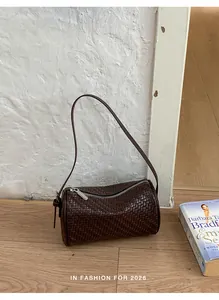 Close-up view of a dark brown retro woven texture barrel bag placed on a wooden floor