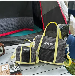 Pair of grey grid pattern outdoor casual tote bags with neon straps on camping table