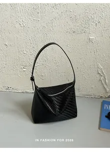 Macro view of black woven underarm bag showcasing minimalist high-end luxury texture