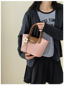 Detail view of a vintage pink canvas handbag with brown leather handles and flower charm