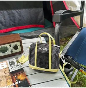 Close-up of a grid pattern tote bag with yellow straps in a stylish camping scene
