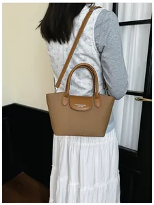 Model carrying a vintage brown leather crossbody handbag against a minimalist interior