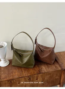 Macro view of woven leather shoulder bags in olive green and brown earth tones.