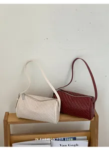 Detailed view of woven texture on cream and burgundy cylindrical shoulder bags