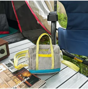 Lightweight grey grid fabric crossbody bag with yellow straps on an outdoor camping table