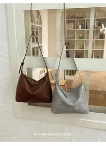 Pair of brown and grey woven underarm bags hanging in a studio setting