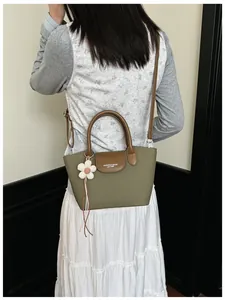 Model wearing retro green canvas handbag with brown leather accents and flower charm