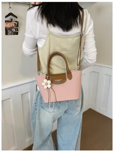 Elegant vintage pink handbag with brown handles and white flower charm shown on model