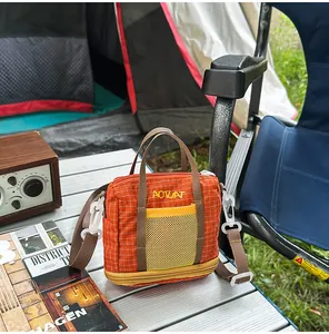 Detail of orange mesh crossbody bag on camping table with vintage radio and magazine