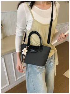 Asian model styling a retro black leather crossbody bag with a dainty flower charm detail