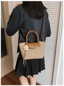 Close-up detail of retro canvas handbag with brown leather trim and flower charm on model