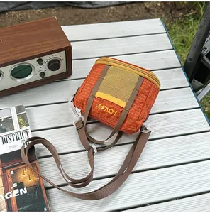 Close-up view of lightweight orange grid crossbody bag displayed on a camping table.