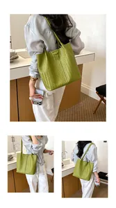 Elegante borsa tote in pelle intrecciata verde indossata da una modella in casa