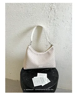Dettaglio della borsa sottobraccio intrecciata beige con stile retrò minimalista