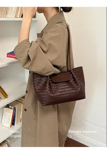 Close-up of the woven texture on a dark brown shoulder bag in a commuter lifestyle scene.