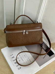 Elegante bruine getextureerde rechthoekige box tas met handvat en zilveren details.