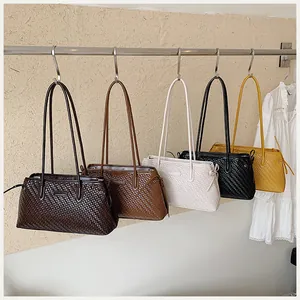 Vista detallada de bolsos de hombro tejidos retro en cinco colores en una barra metal