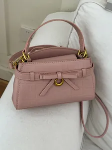 Elegante roze handtas met steenpatroon, strikdetail en goudkleurige hardware