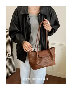 Detail view of a stylish brown woven tote bag featuring a minimalist shoulder strap design.