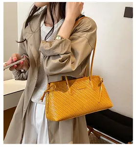 Detalle de un bolso de hombro vintage trenzado amarillo llevado por una modelo real