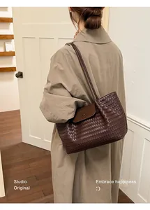 Close-up of a stylish brown woven leather tote bag carried over the shoulder in a lifestyle setting
