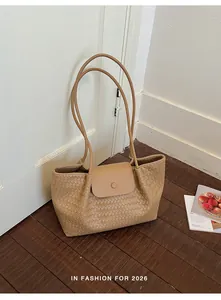 Detailed view of beige woven tote bag leaning against a door in a lifestyle setting
