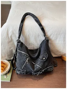 Nahaufnahme einer gewaschenen schwarzen Denim-Hobo-Tasche mit modischen Reißverschlüssen.