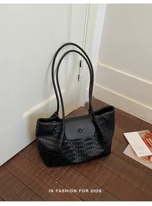 Detailed view of the black woven texture and flap closure on this commuter tote bag