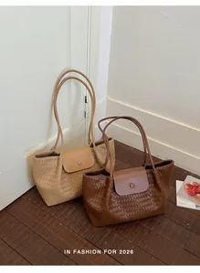 Close-up of brown and tan woven tote bags with flap closure and long straps