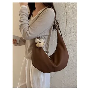 Detail view of a stylish vintage brown crescent shoulder bag worn by a model with charm