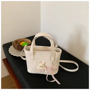 Detail van de crème gewatteerde emmer tas met een schattige konijnenbedel en roze strik
