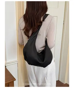 Detailed view of the minimalist black pleated hobo bag worn as a vintage shoulder bag