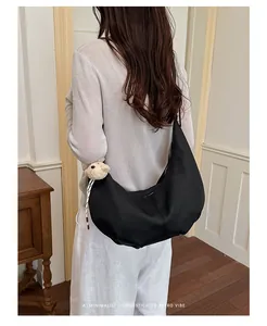 Detailed shot of a stylish black pleated hobo bag with a cute plush bear charm