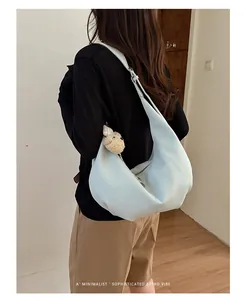 Close-up of minimalist light blue pleated hobo bag with a cute teddy bear charm
