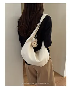 Woman wearing a creamy-white pleated underarm hobo bag with cute plush puppy keychain.
