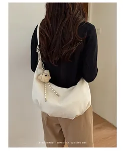 Minimalist white faux leather hobo shoulder bag with a plush bear charm for a retro aesthetic
