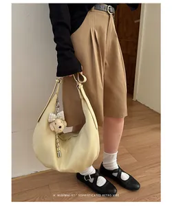 Sophisticated pleated hobo bag with teddy charm shown in a minimalist outfit