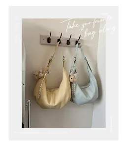Lifestyle scene showing pleated crescent bags in yellow and blue hanging on a wall hook