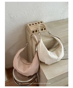 Detail view of two pleated underarm bags in pink and beige, featuring a retro vibe
