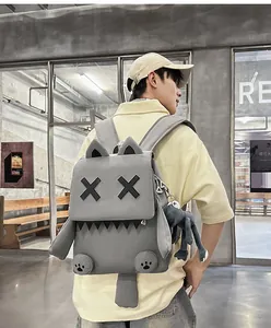 Rear view of a male model wearing a gray cartoon monster backpack with a plush charm