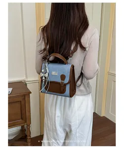 Vista trasera de una pequeña mochila elegante de mezclilla y cuero usada por una modelo.