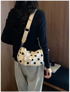 Close-up van een stijlvolle beige crossbodytas met stippen op een model