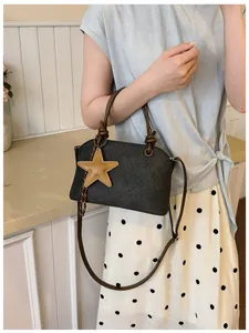 Gros plan d'un sac à bandoulière gris texturé avec un pendentif étoile jaune décoratif