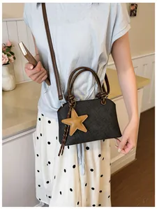 Sac à main élégant gris foncé texturé avec bandoulière marron et charme étoile jaune.