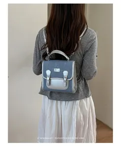 Detalle de una pequeña mochila de mezclilla con toques metálicos plateados en modelo