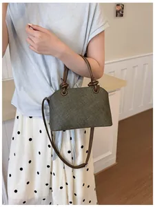 Détail d'un sac à bandoulière vert olive texturé avec des poignées à nœuds élégantes.