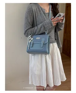 Detalle de bolso bandolera de mezclilla azul usado por modelo con cárdigan gris