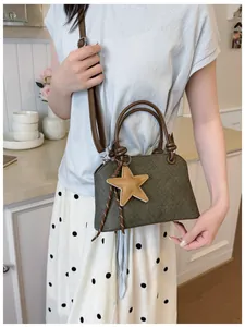 Détail d'un mini sac à main vert olive avec breloque étoile porté par un modèle