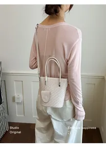 Elegant cream woven bucket bag shown on model for a stylish summer commute look